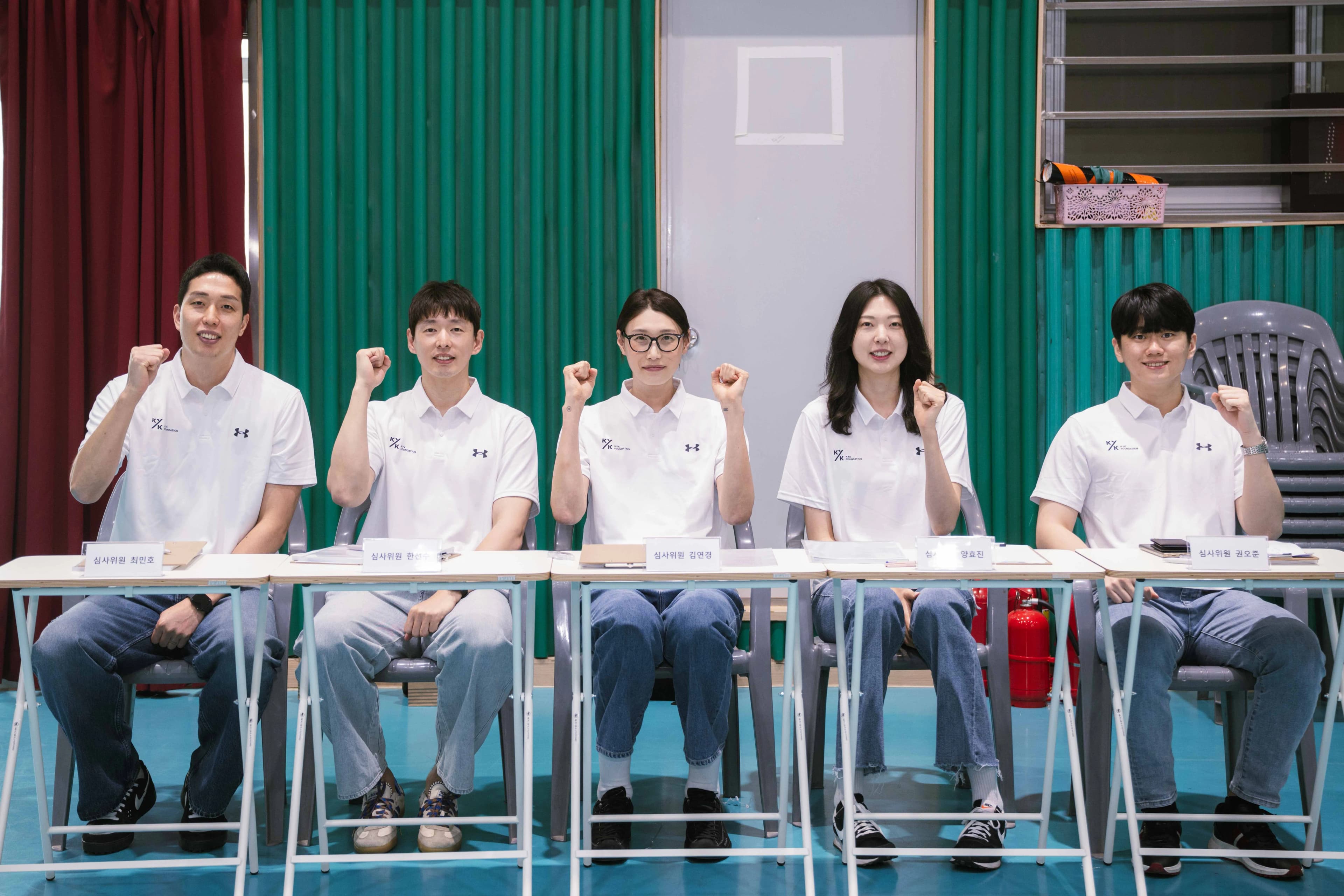 Five judges seated in a row with their fists raised